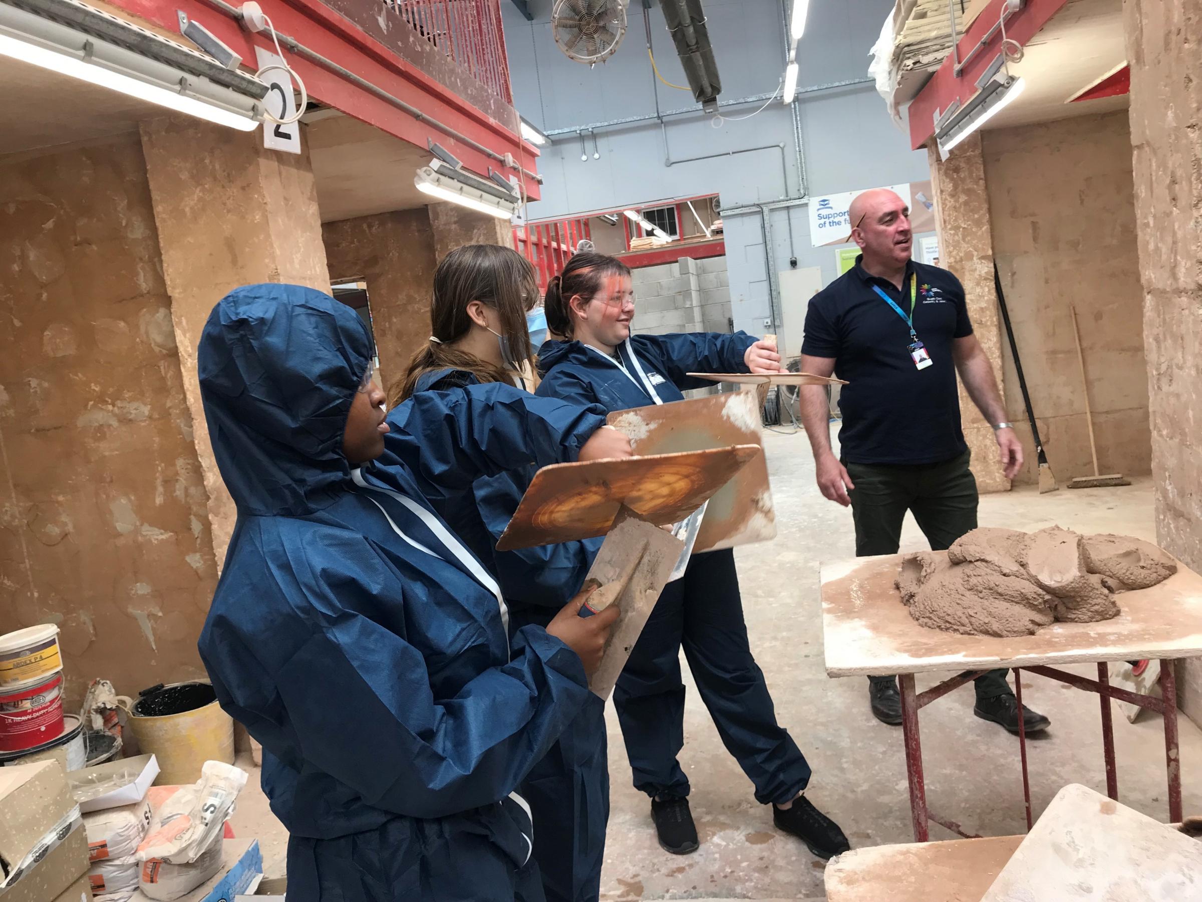 The girls have a go at plastering.