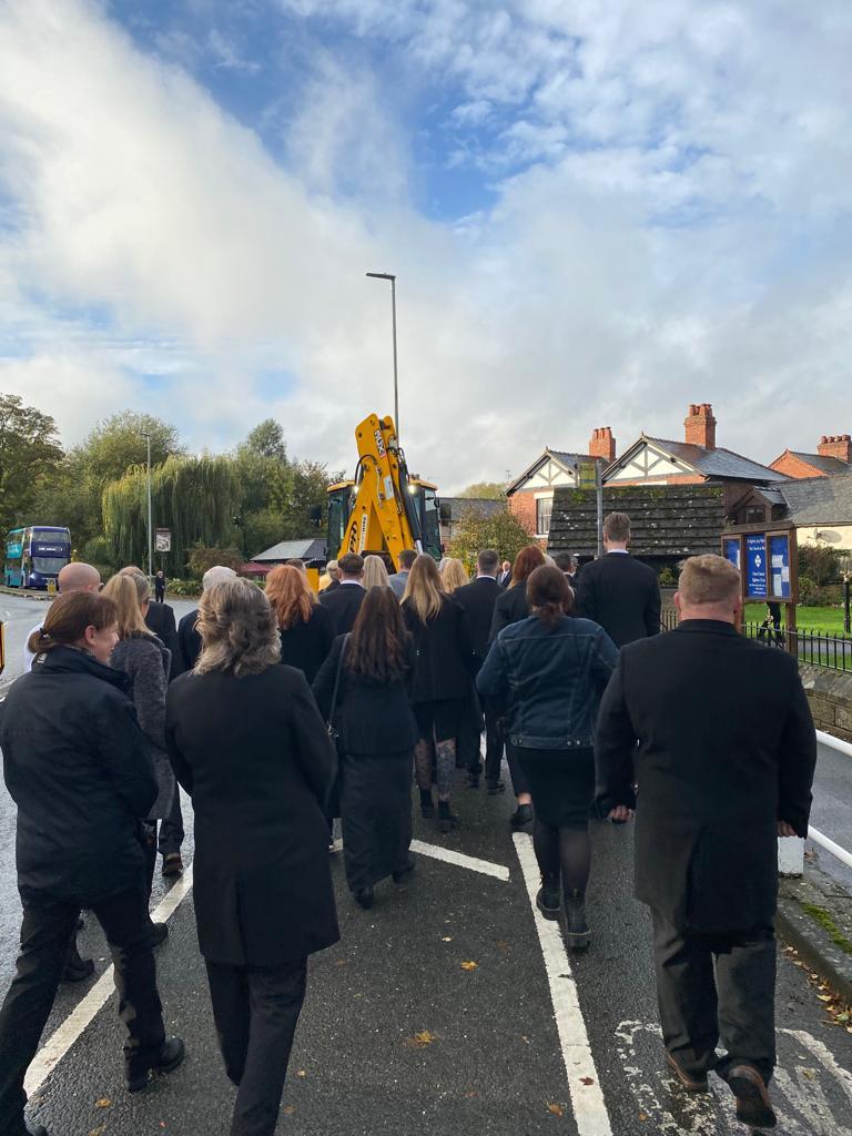 Family and friends walk behind the JCB carrying Raymond Goodlet to Christ Church in Rossett.