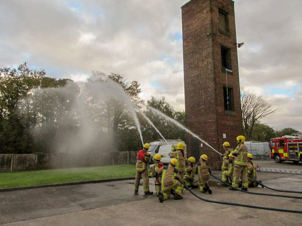 The students practice using the fire hoses.