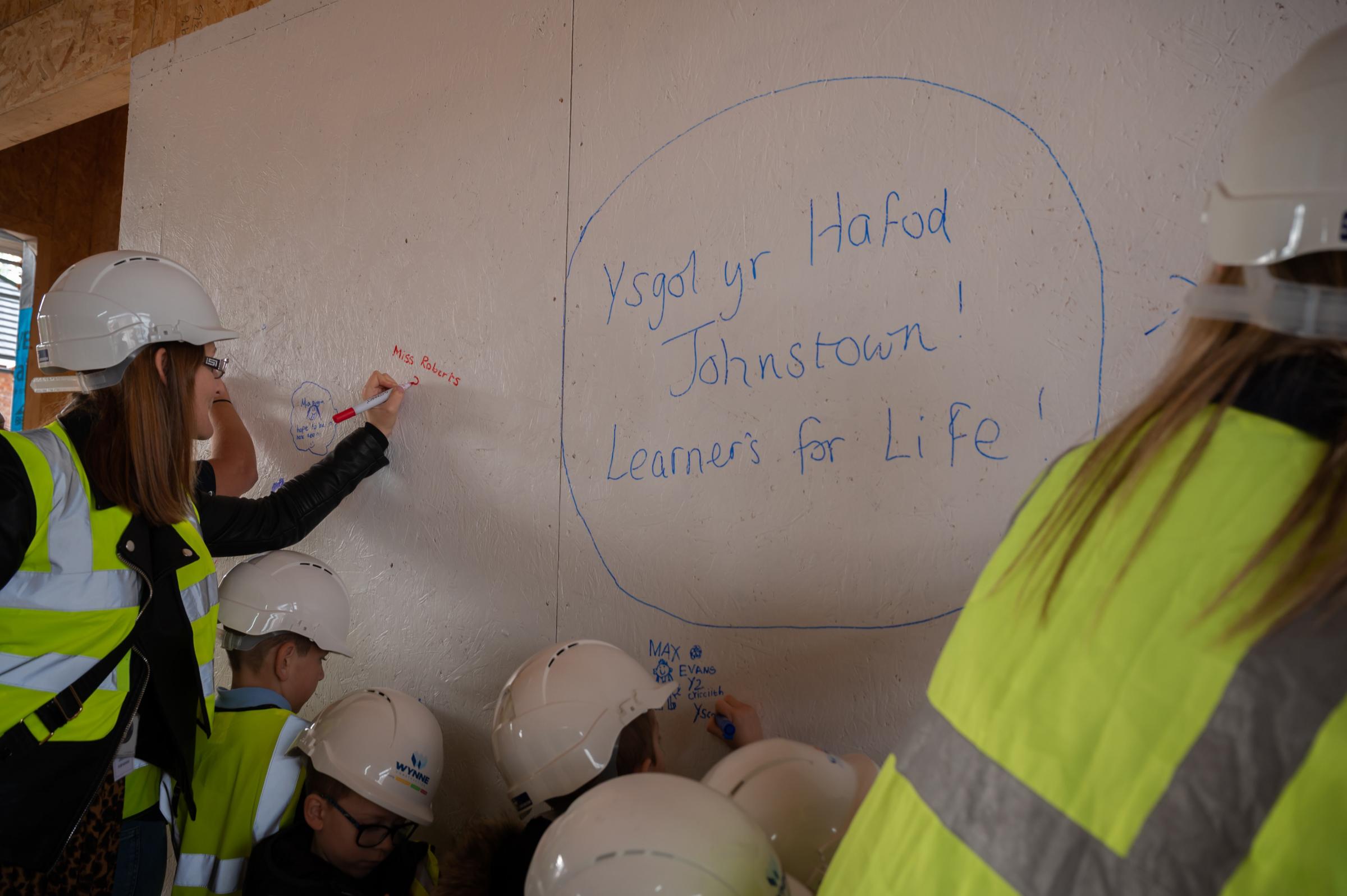 Pupils from Ysgol Yr Hafod sign their name into history during the SIP signing ceremony held by Wynne Construction during a tour of the development.