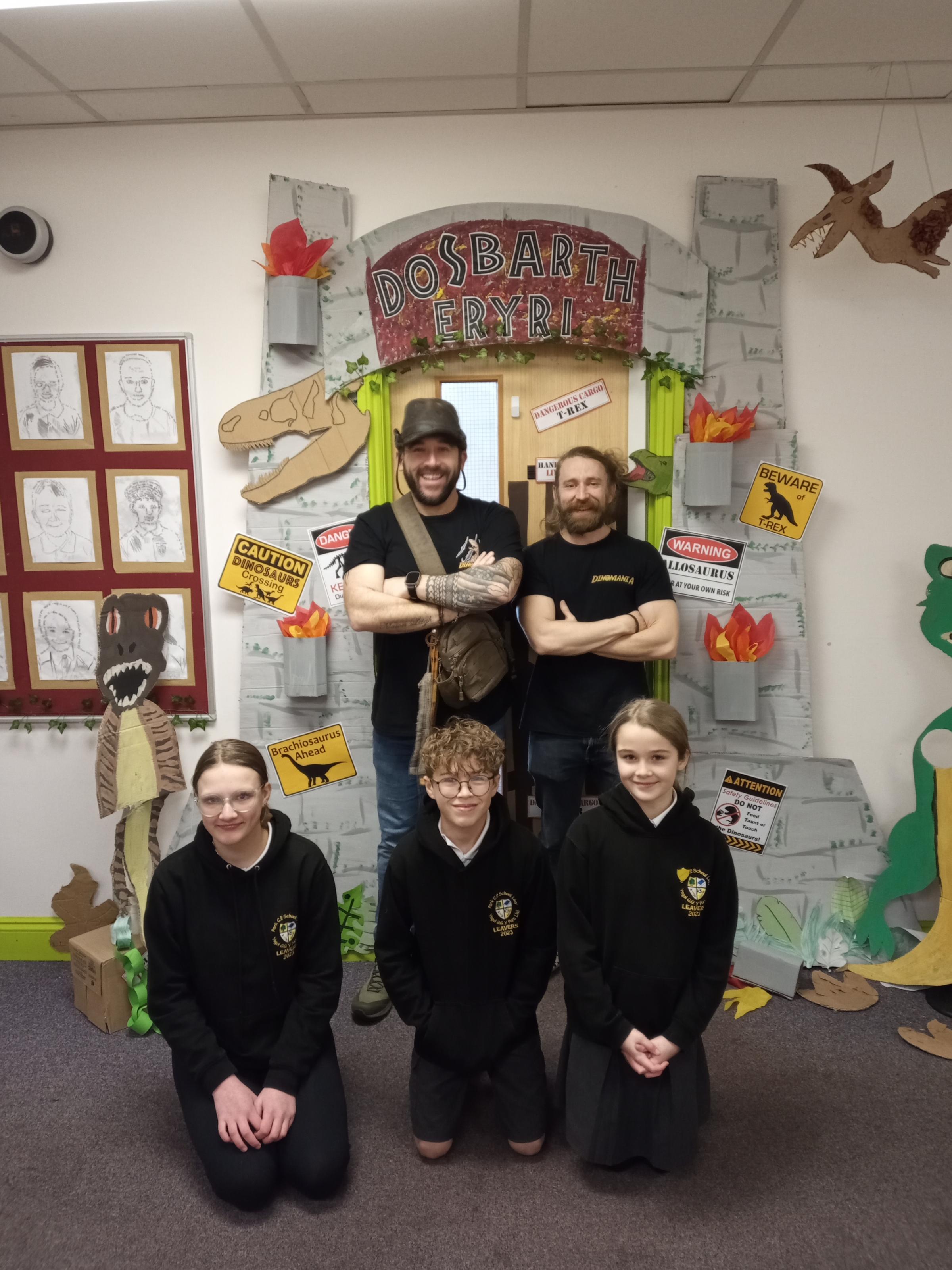 Dinomanias Ranger Chris and Ranger Andy, with deputy head girl Esmae Gill, head boy Samuel Prytherch and head girl Amelia Jones, outside the brilliantly decorated classroom door..