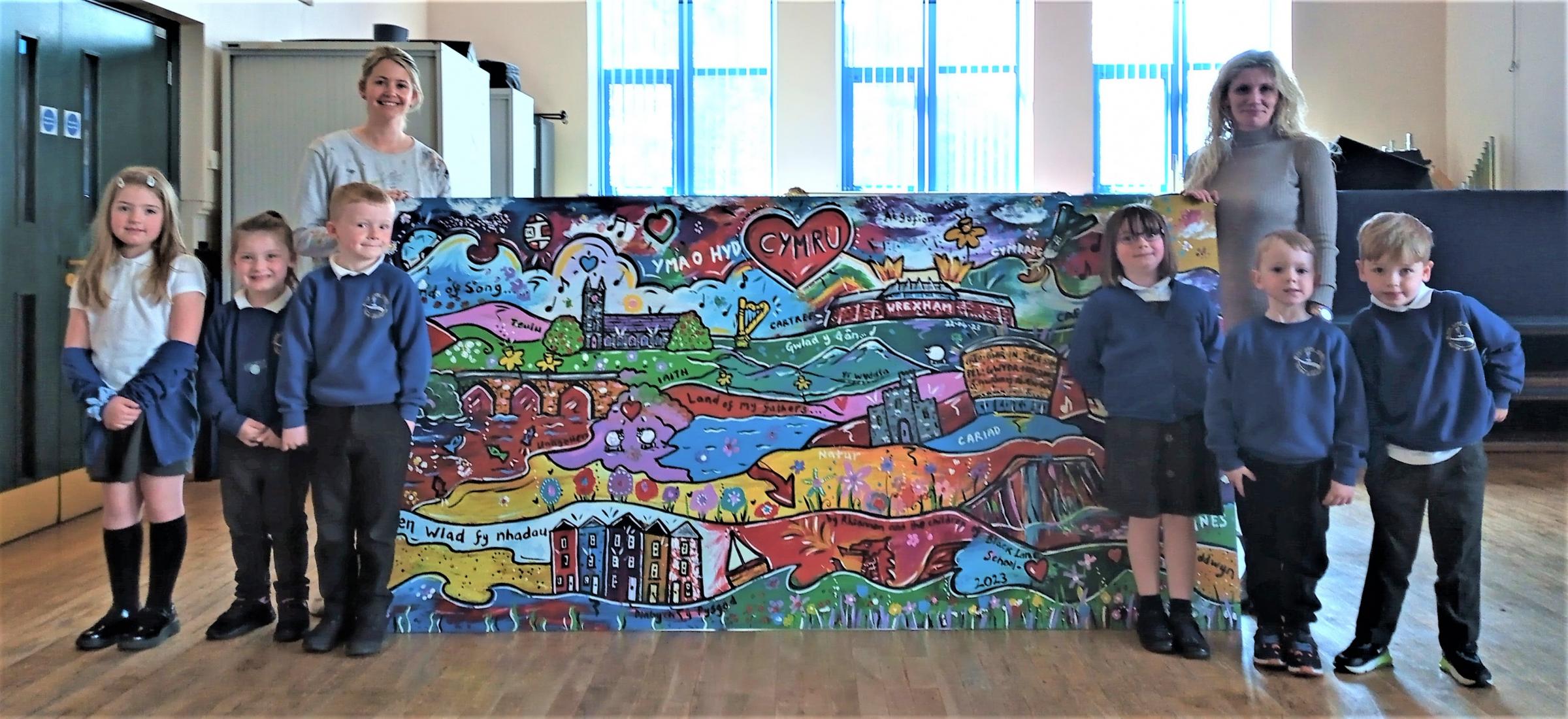 Artist Rhiannon Roberts and Black Lane CP School headteacher Rebecca Fox with pupils and the new Wales themed artwork.