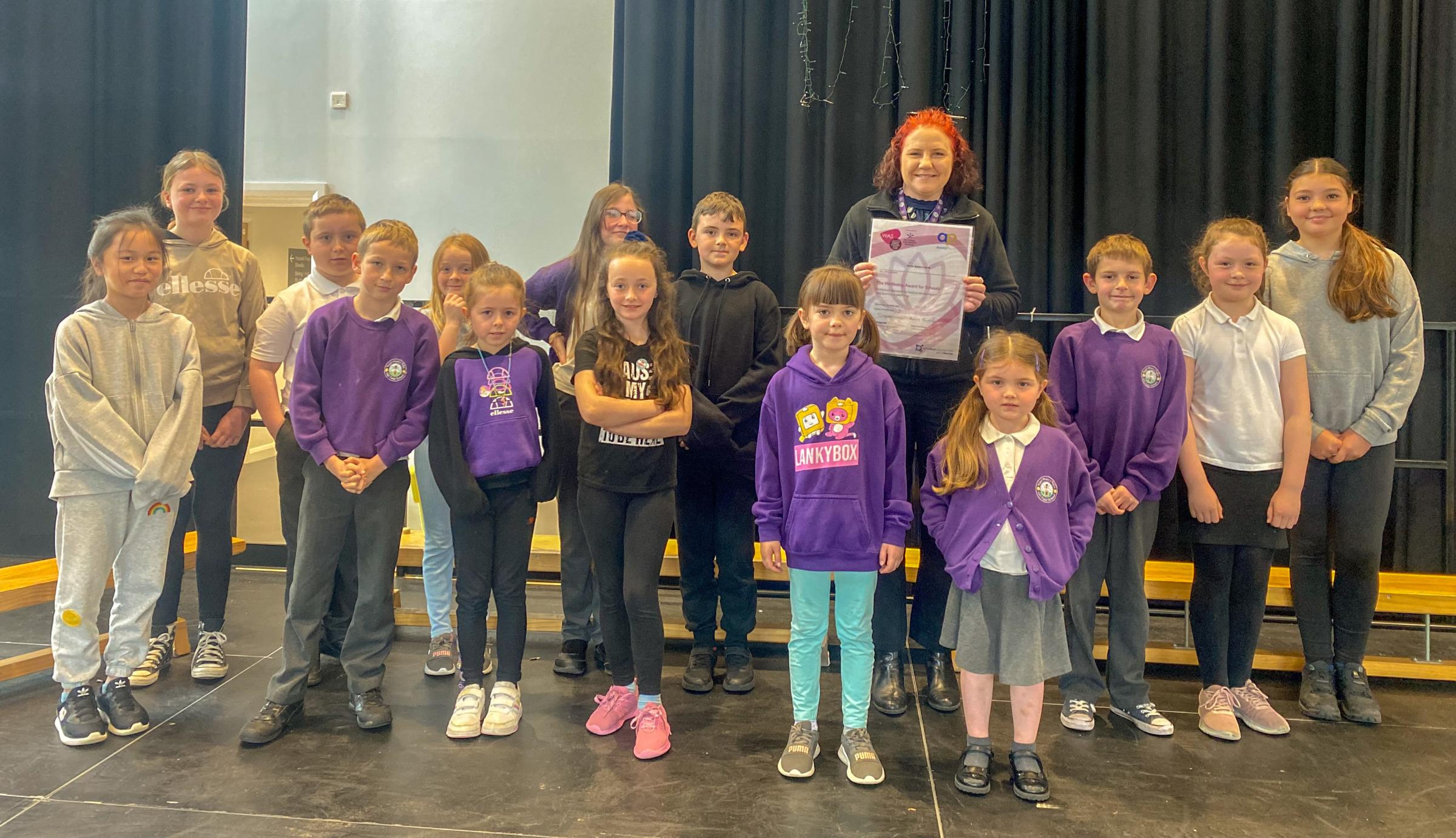 Shirley Allman holding The Wellbeing Award For Schools certificate with members of the change team at Ysgol Maes y Felin.