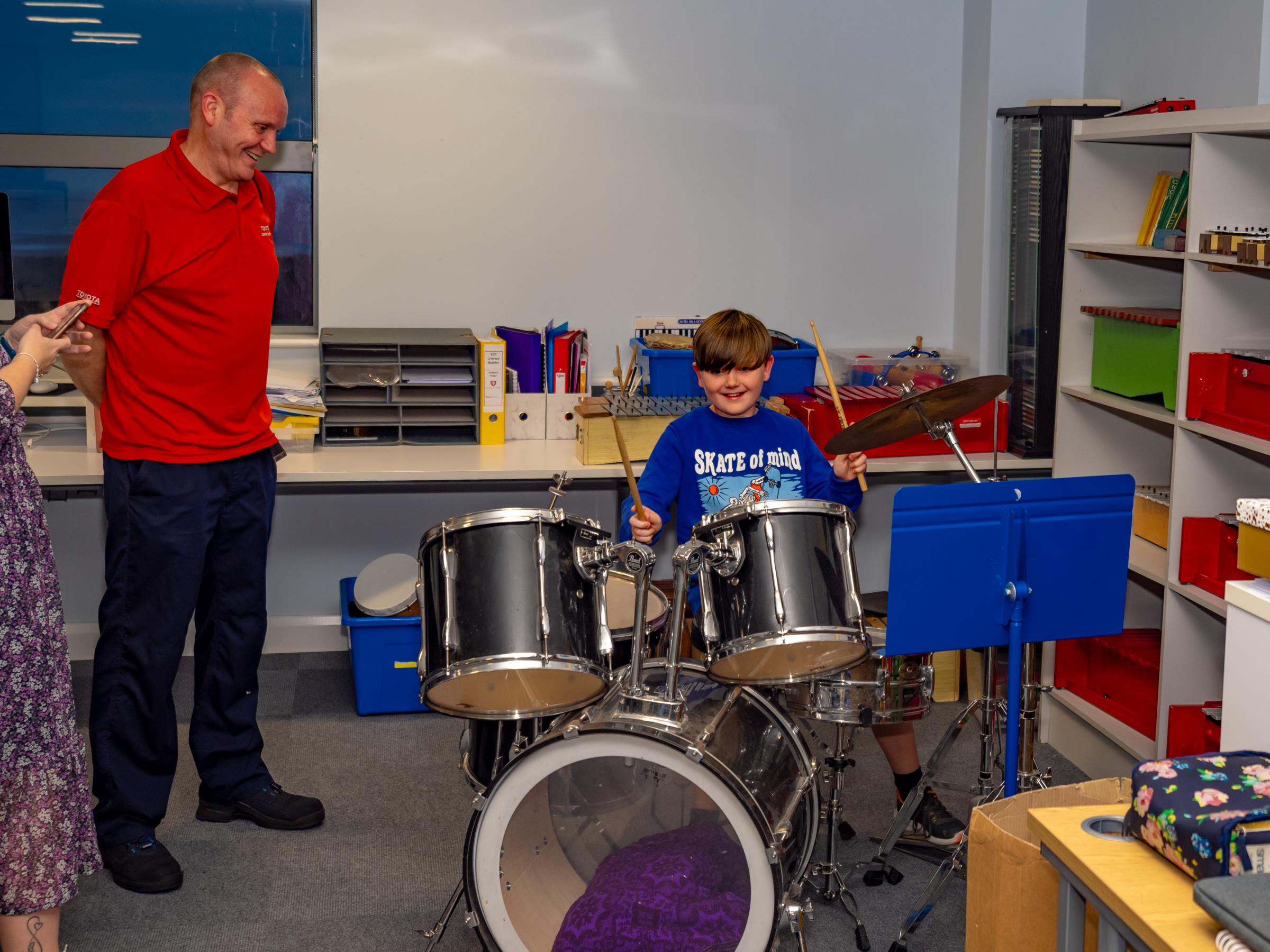 A prospective student gives the drum kit a try in the music department.