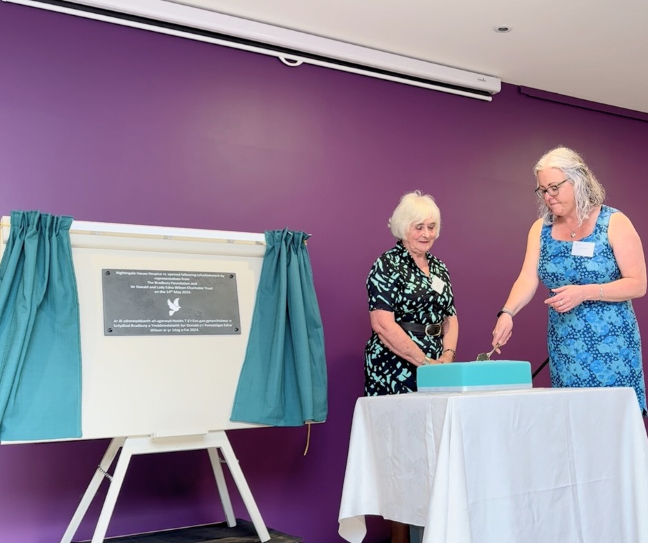 Eluned Griffiths watches Andrea Chesworth cut the cake at Nightingale House Hospice.