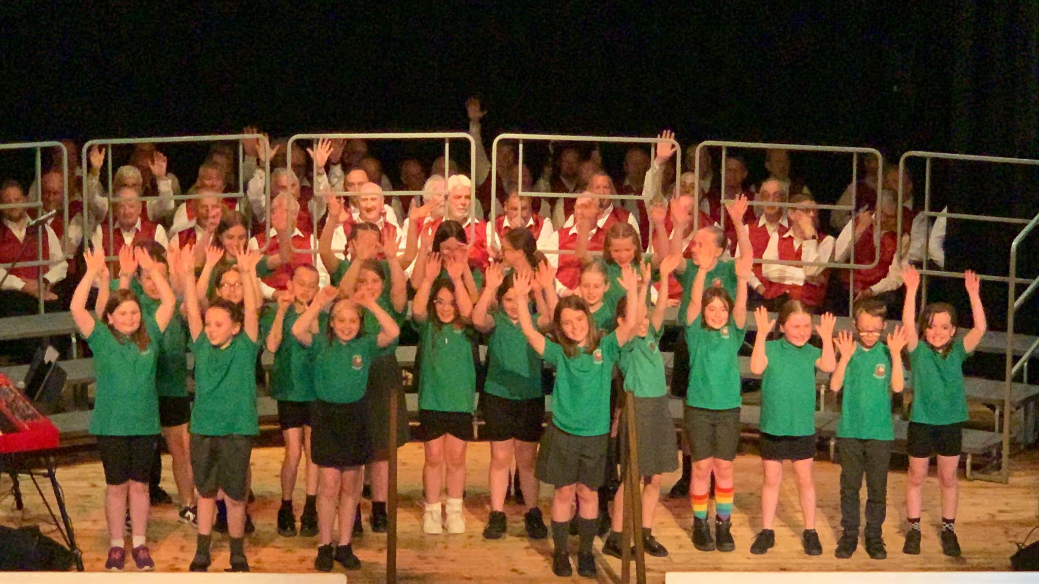 Members of Froncysyllte Male Voice Choir with pupils from Ysgol Acrefair.