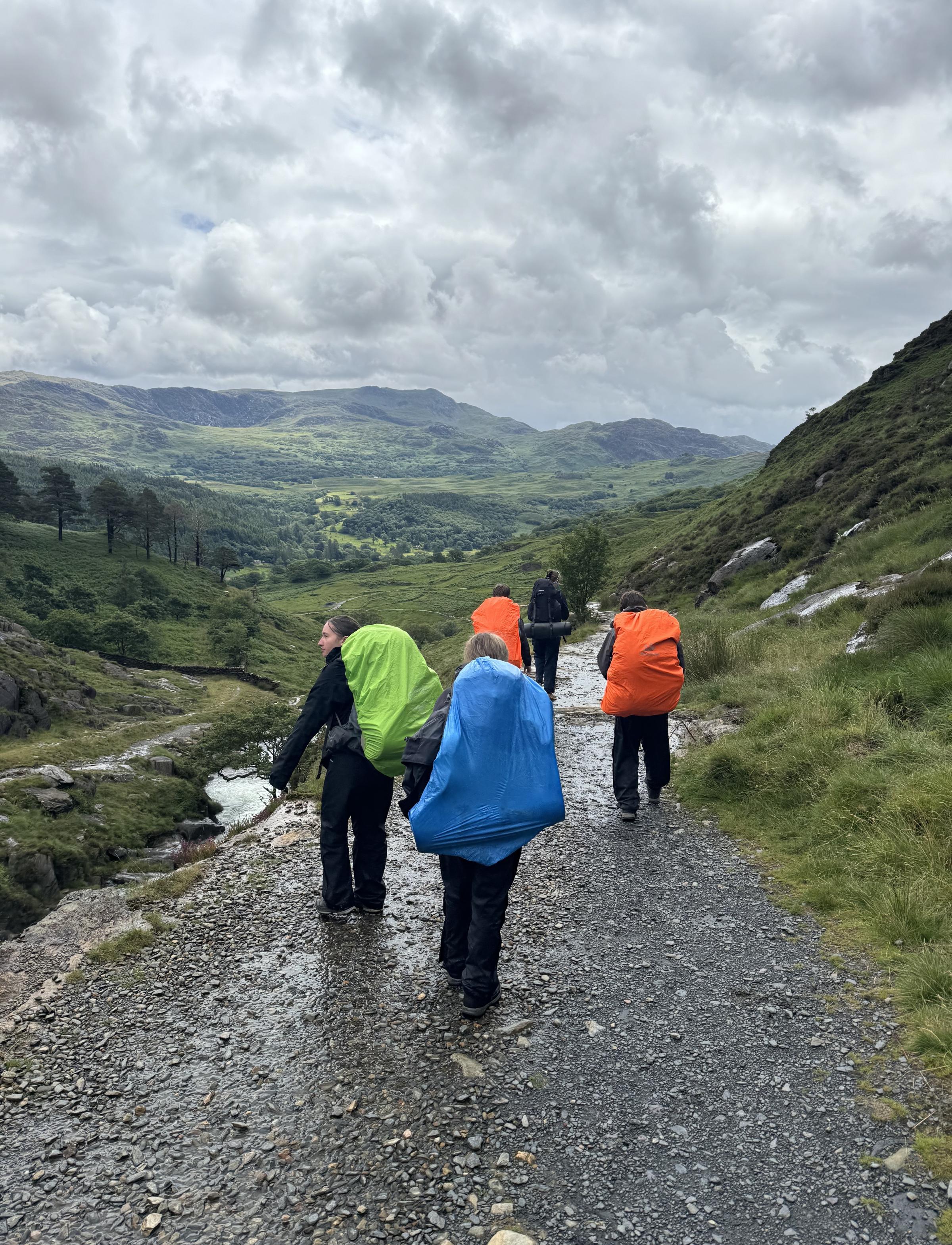 The group on a hike, with rucksacks protected against the weather in waterproof covers.