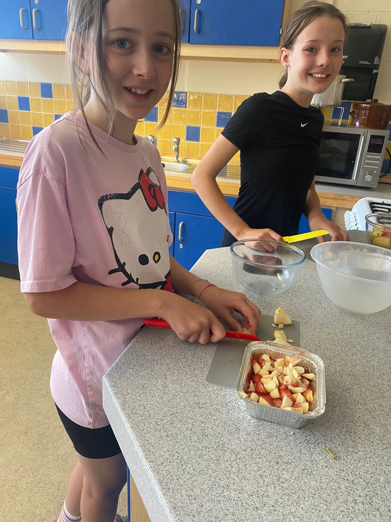 Beatrix Evans and Matilda Cooper make a fruit salad in a cooking session.